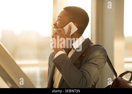 Afro Financier Talking on Phone in Airport Terminal Stock Photo