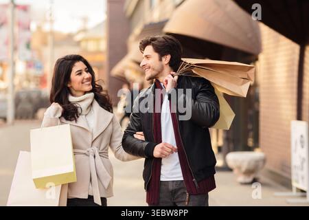 Happy shopaholics walking with shopping bags after making purchases Stock Photo