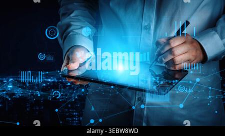 A business professional engages with a tablet and digital pen, analyzing data through graphs and charts against a high-tech urban backdrop at night Stock Photo