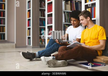 Two Students Collaborating on a Laptop in a Library Study Area During the Afternoon Stock Photo