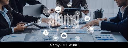 A modern office setting where a diverse team collaborates on charts and data analysis, highlighting technology and teamwork for effective business Stock Photo
