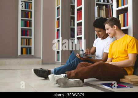 Two Students Collaborating on a Laptop in a Library Setting During the Afternoon Stock Photo