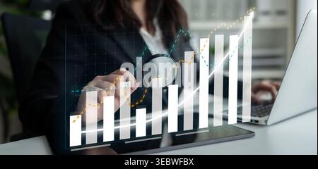 A business professional examines data trends using a magnifying glass on digital bar graphs. This image conveys analysis and growth in a modern office Stock Photo