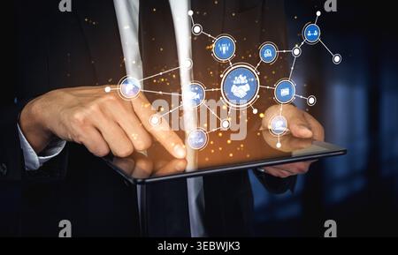 A business professional engages with a digital tablet displaying interconnected icons representing innovation, teamwork, and strategy in a modern Stock Photo