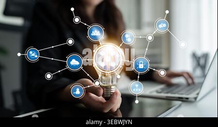 A business woman holding a glowing light bulb symbolizing innovation amidst a digital network. This image captures the essence of creativity and Stock Photo
