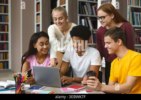 Group of Students Collaborating on Laptop in Modern Library During Afternoon Study Session Stock Photo