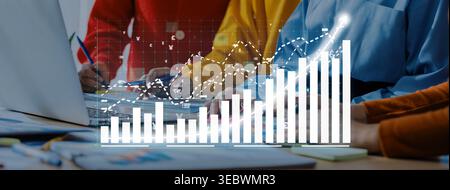 A diverse business team collaborates in a modern office, analyzing financial growth data through charts and graphs displayed on a laptop, ensuring Stock Photo