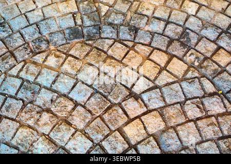 Top down view of weathered stone pavers arranged in a radial pattern on a historic street in Jew Town. Atmospheric and textured. Stock Photo