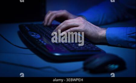 Hands Typing on a Keyboard in a Low Light Setting During Late Night Work Stock Photo