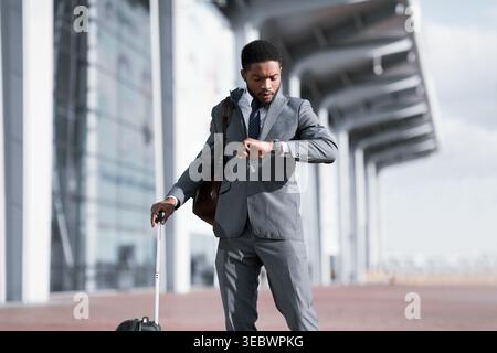 Business Traveler Checking Time On his Wristwatch At Airport Stock Photo