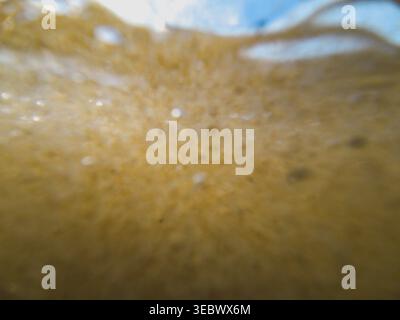An underwater perspective looking up toward the surface, showing a dense cloud of white air bubbles and stirred-up sand. Stock Photo