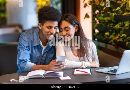 Young Couple Enjoying Time Together While Browsing on a Smartphone in a Cozy Cafe Stock Photo