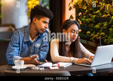 Young People Collaborating on School Project in a Modern Cafe During Afternoon Stock Photo