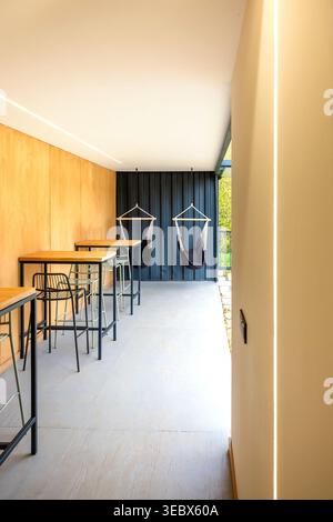 Empty modern outdoor lounge cafe interior with long tables and swing chairs Stock Photo