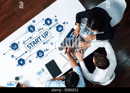 A diverse team collaborates on a startup business plan, utilizing laptops and documents at a modern office table, illustrating innovation and Stock Photo