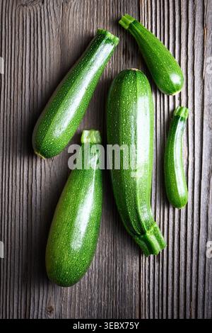 Fresh zucchini on wooden background, minimal composition, organic vegetables concept. Green squash top view, natural texture, healthy ingredient Stock Photo