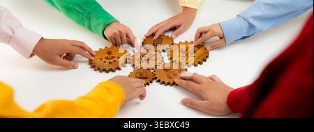 Collaborative Learning Activity with Diverse Hands Engaging with Wooden Gears Displaying Creative Designs in a Classroom Setting. Amity Stock Photo