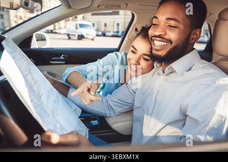 Couple Plans Trip While Sitting in Car and Looking at a Map Together Stock Photo