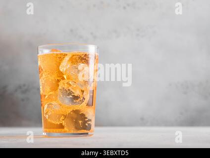 Glass of cold natural apple cider with ice cubes on light table Stock Photo