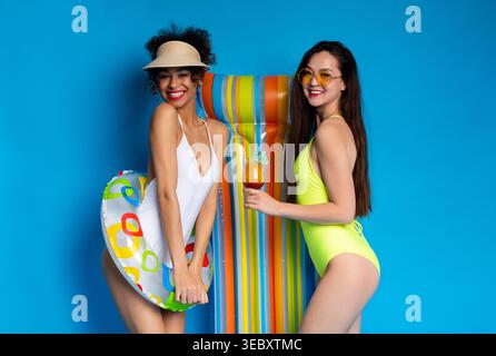 Two Friends Enjoying Summer at the Pool With Colorful Float and Refreshing Drinks Stock Photo