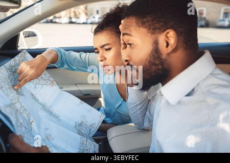 Young Couple Exploring a Map While Sitting in a Car During a Road Trip Stock Photo