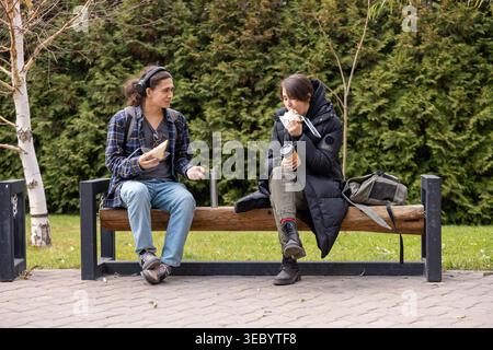 College students having lunch on park bench Stock Photo