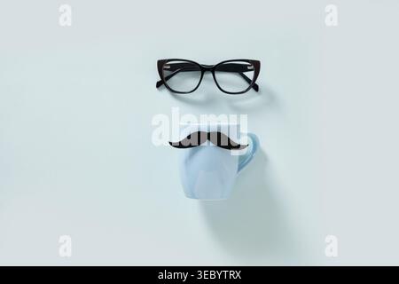 Eyeglasses and white mug with mustache arranged on light background, creative minimal composition, lifestyle concept, copy space, top view. Father day Stock Photo