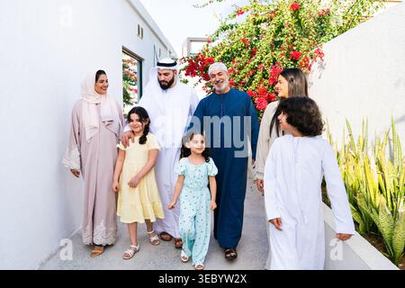 Arab family of three generations walking together outside their home, connecting and bonding while enjoying the sunny weather, representing family val Stock Photo