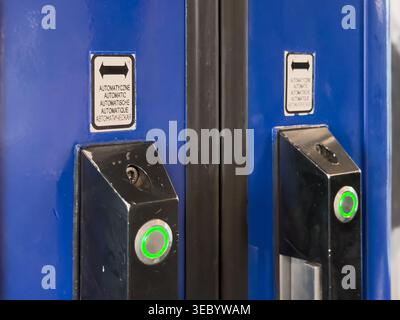 Two identical metal entry systems for automatic doors feature illuminated green buttons and multilingual Automatic signage, clearly indicating public Stock Photo