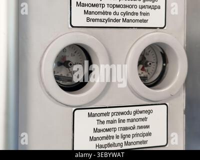 Close-up view of two identical pressure gauges mounted on a white industrial panel, indicating precise measurement and monitoring functionality Stock Photo