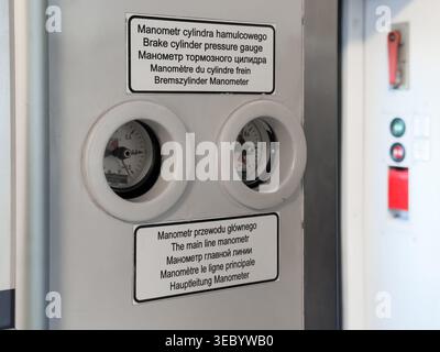 Close-up of two circular pressure gauges, labeled in multiple languages, mounted on a machine's panel, signaling operational status and system monitor Stock Photo