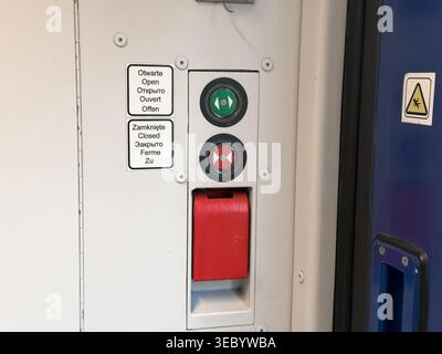 Multilingual labels on train door control panel, featuring green open and red closed buttons, signaling passenger transit safety and operational statu Stock Photo