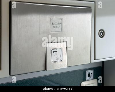 Close-up of a contemporary hand dryer unit, constructed from brushed stainless steel, indicating a focus on sanitation and convenience in transportati Stock Photo