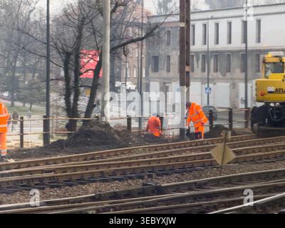Gliwice, Poland - December 3, 2025: Staff in neon gear fix rails by soil, helping build safe city transit system and better public traffic flow site Stock Photo
