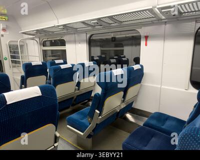 Krakow, Poland - December 3, 2025: Interior view of a clean, modern train compartment with rows of blue fabric seats, white headrests, and large windo Stock Photo