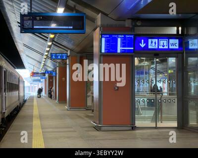Krakow, Poland - December 3, 2025: A modern train station platform features digital departure boards displaying arrival and departure information for Stock Photo