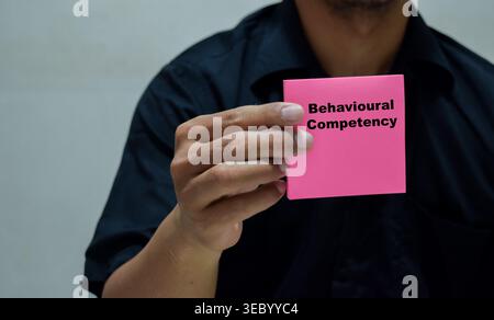Businessman holds in hands a card with the name of the behavioral competency. Stock Photo