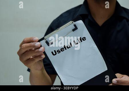 Businessman holds in hands a clipboard with the name of the useful life. Stock Photo