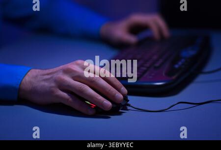 Person Using Computer Mouse and Keyboard in Dimly Lit Room During Evening Hours Stock Photo