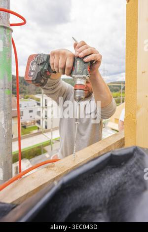 Construction worker drilling a hole in a piece of wood on a construction site, residential renovation, Nagold, Calw district, Germany Stock Photo