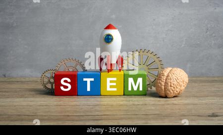 A rocket ship and gears placed on STEM letter blocks next to a brain model for science, technology, engineering, and math education. Stock Photo
