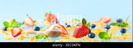 Concept of healthy gluten free breakfast with berries,natural yogurt and corn flakes on blue background. Stock Photo