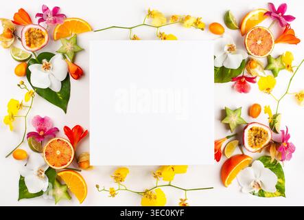 Colorful pattern of whole and sliced exotic fruits with tropical leaves and flowers. Summer concept with fruits on white background. Top view. Stock Photo