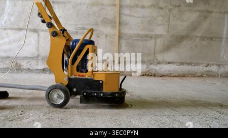 Worker Grinding Concrete Floor With Machine Stock Photo