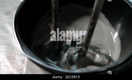 Industrial mixer blending gray concrete mortar in a bucket Stock Photo