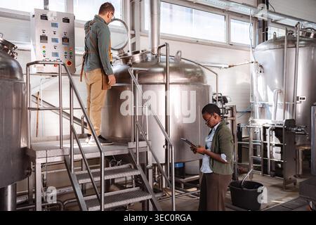 Factory workers checking manufacturing process in a modern craft beer brewery Stock Photo