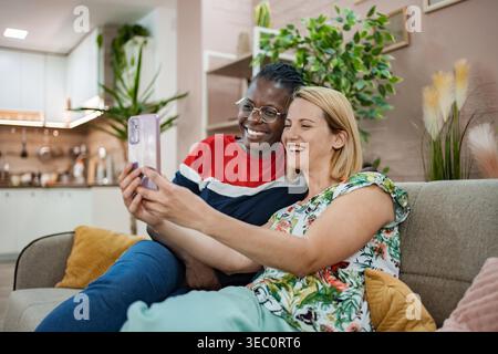 In a warm, inviting space filled with plants and soft decor, two friends share laughter over a video call, capturing a moment of joy and connection. Stock Photo