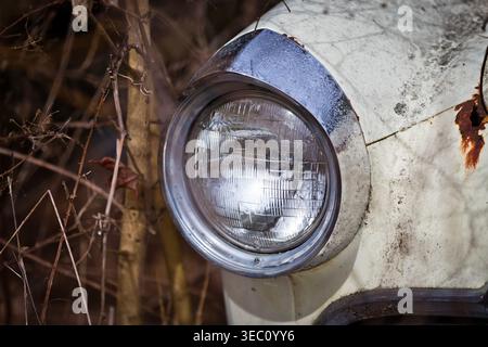 Close-up view of a vintage truck outdoors in a rural setting, showing fading paint, peeling sheet metal, rusted edges, and worn details that reveal ye Stock Photo