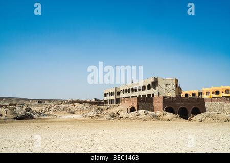 Marsa alam, egypt 21 april 2026: unfinished buildings and rubble in the arid desert landscape under a clear blue sky, showing development and abandonm Stock Photo