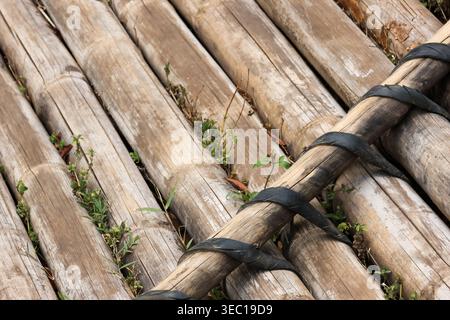 Close up view of weathered brown bamboo pole arrangement bound together with black strap showing rough wood texture and natural pattern evoking calm e Stock Photo